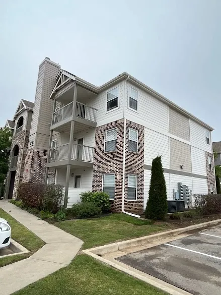 Three story brick and siding apartment building with freshly painted trim and balconies