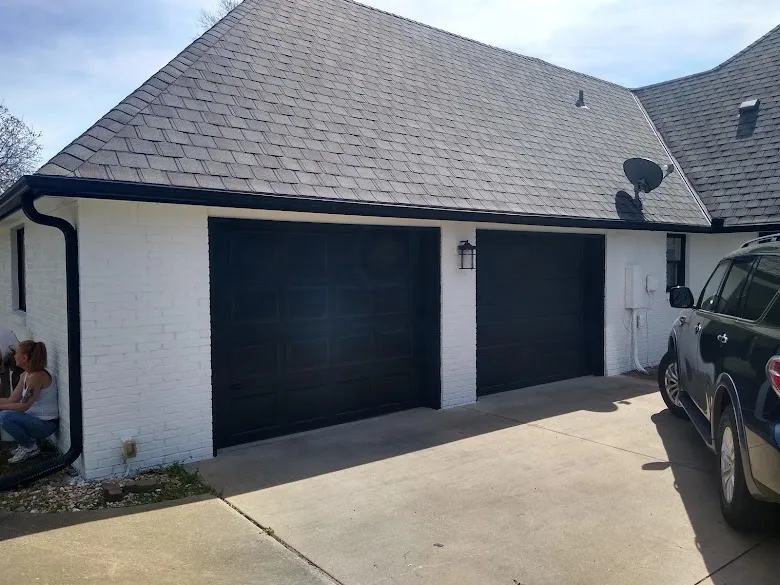 Painted white brick with black garage doors and black gutters