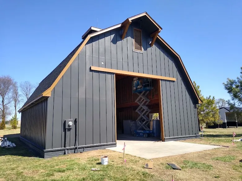 Board-and-batten barn painted dark gray with wood-tone trim, painted by David Woodall Painting